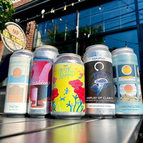 Five colorful craft beer cans from Underground Coffee & Ales sit on a table outdoors.